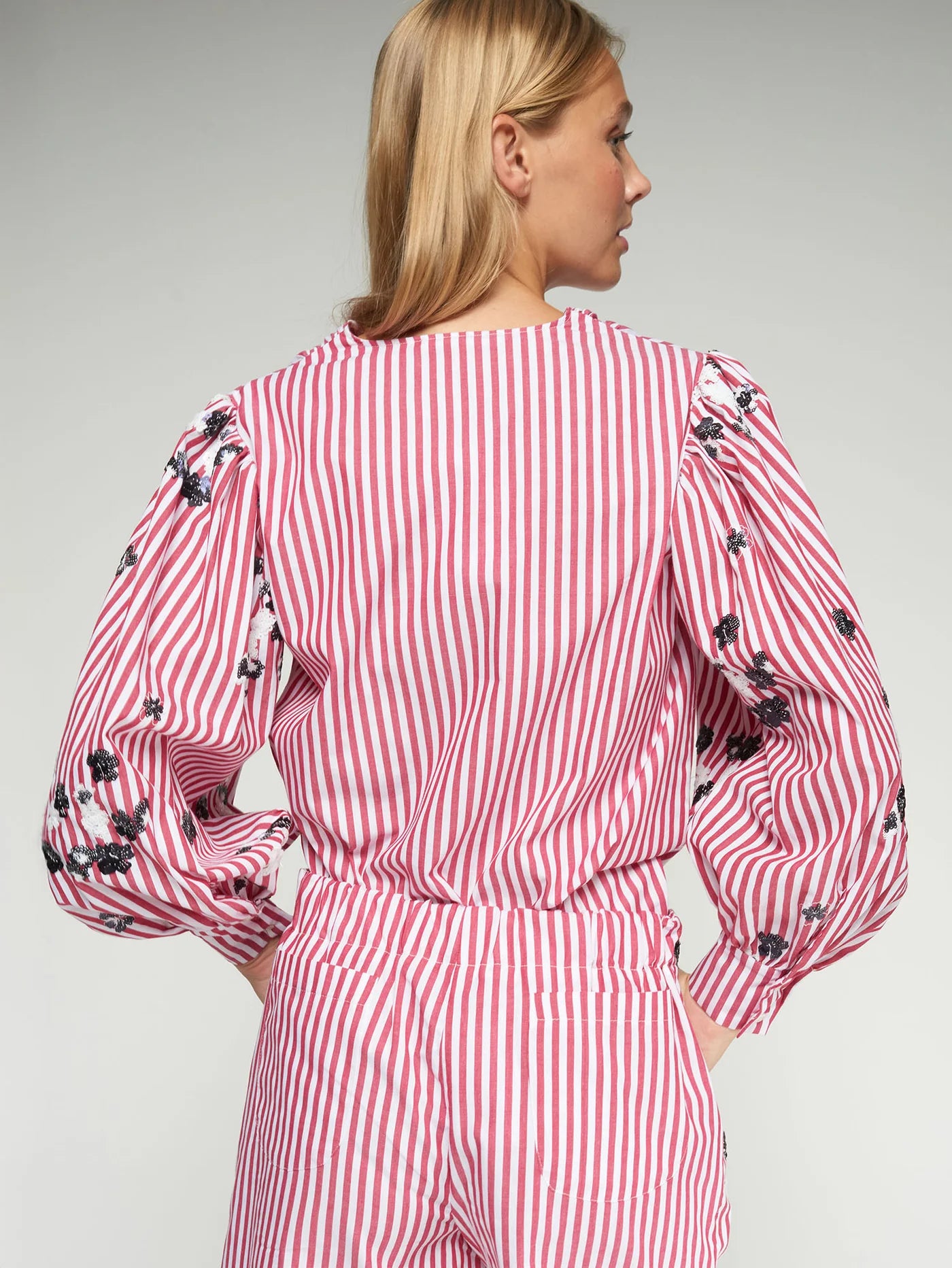Woman wearing a red and white striped dress with black floral patterns on a gray background